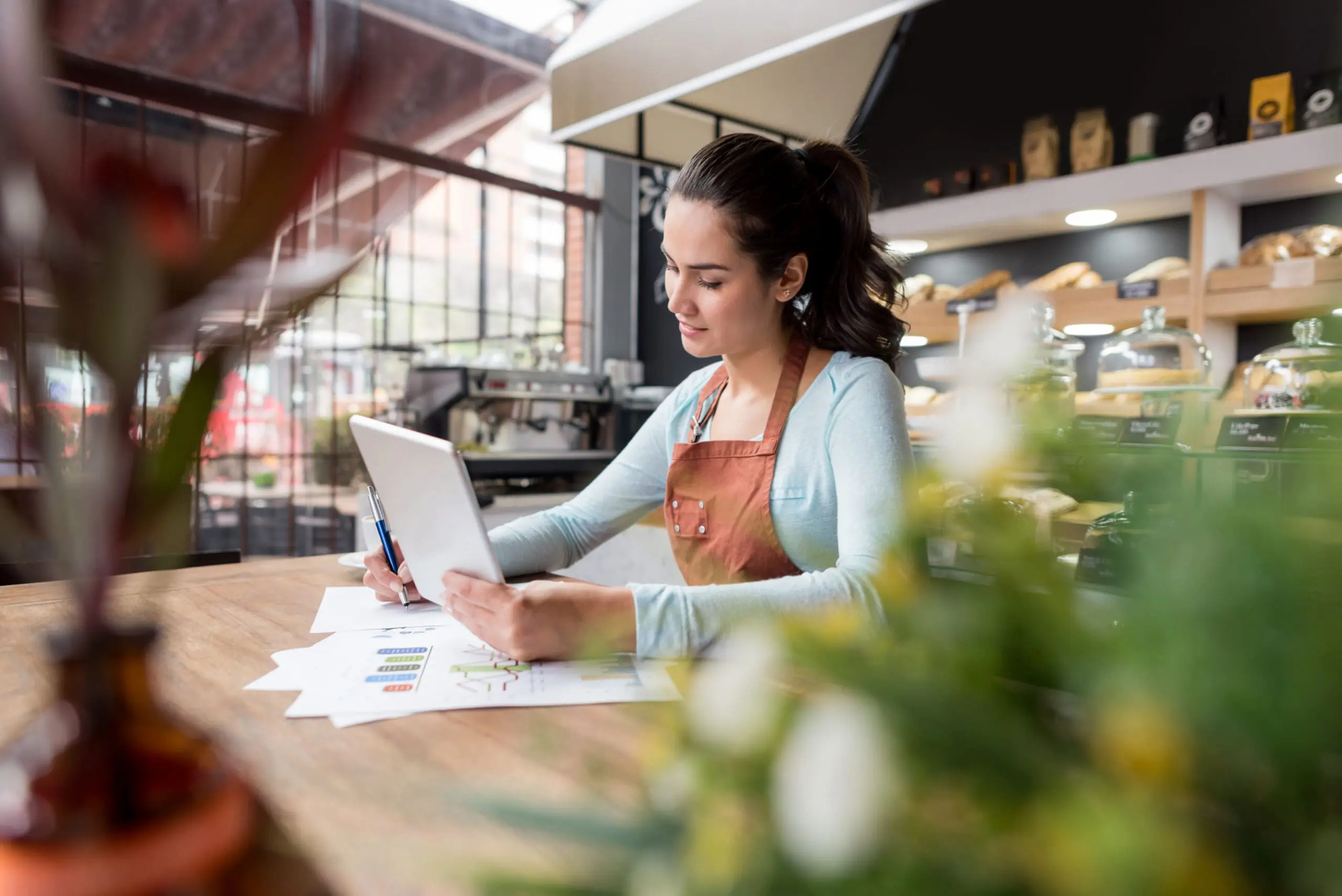 Female barista in coffee shop holding and IPad