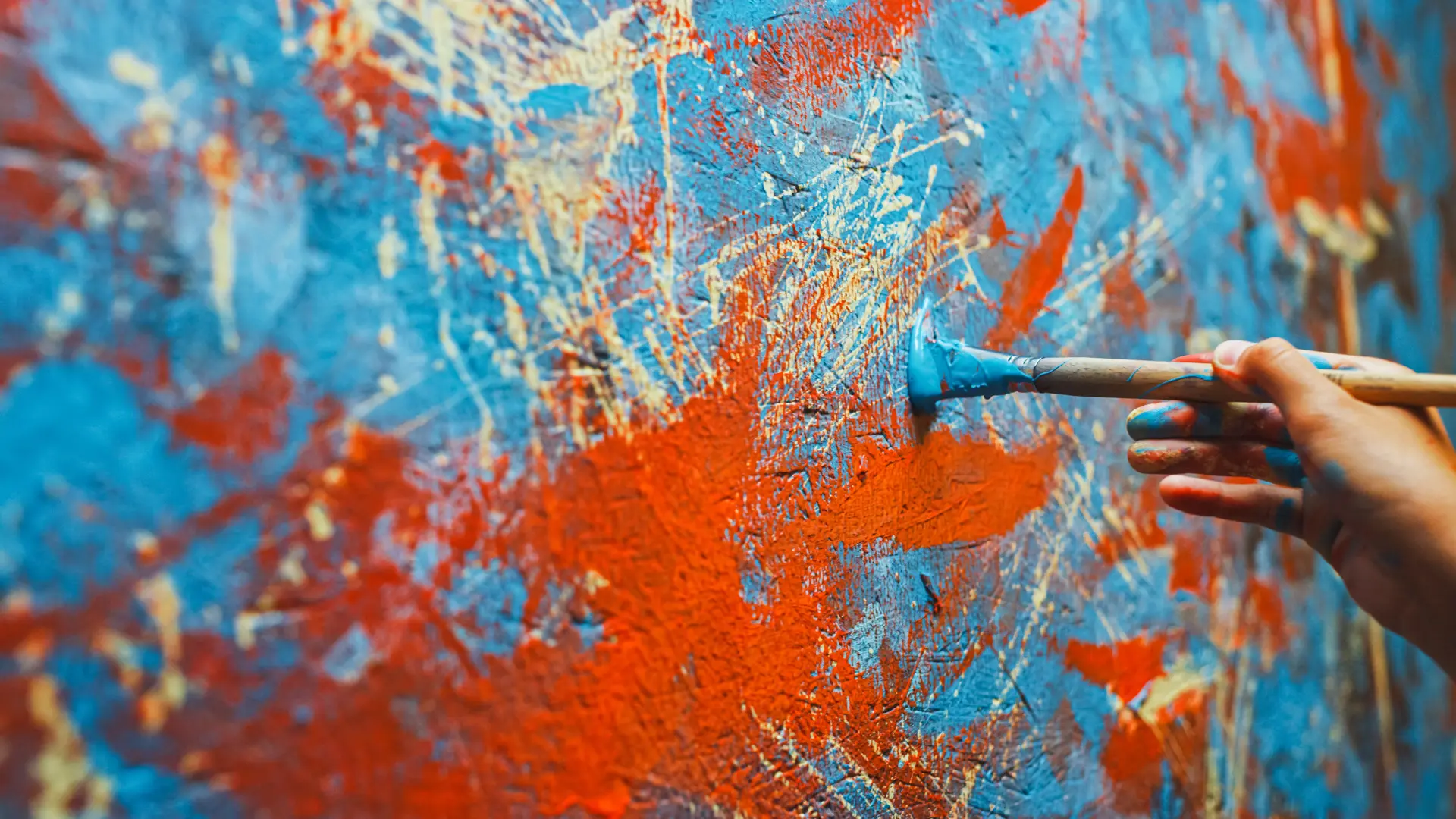 Person painting red and blue streaks on a canvas