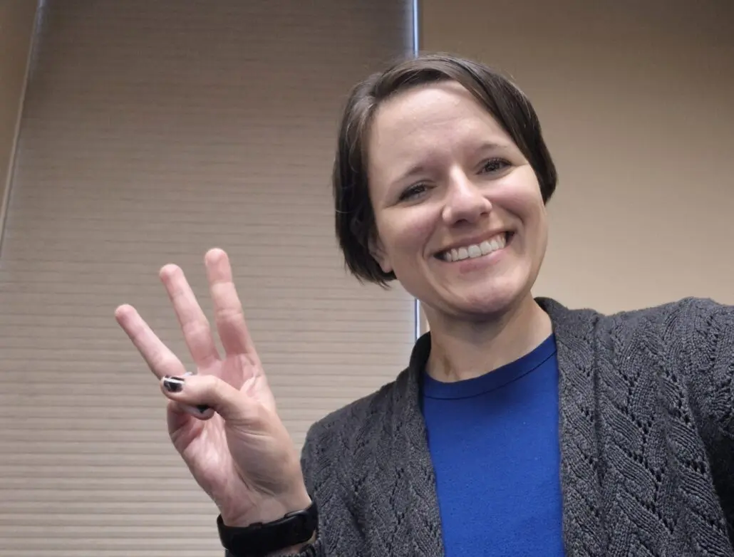 woman holds up 3 fingers