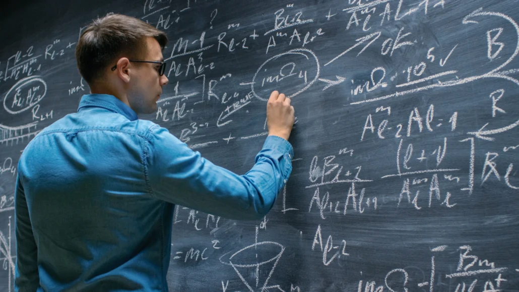 Male student doing math at chalkboard