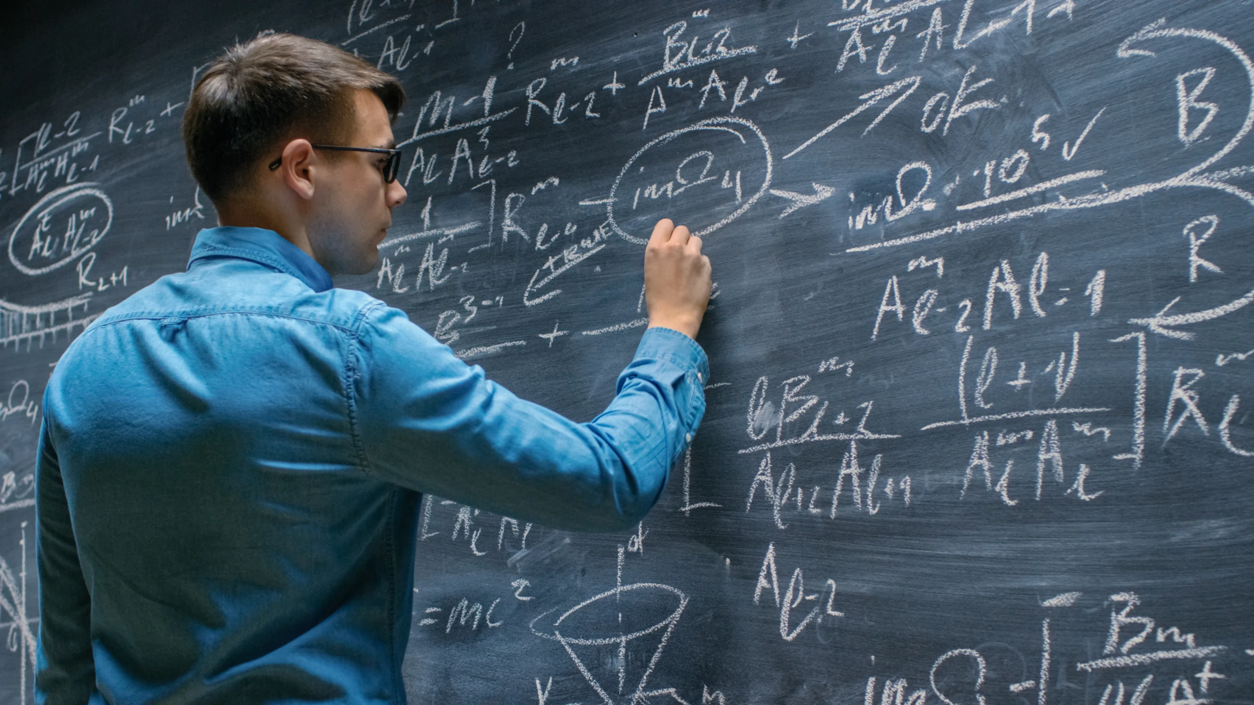 Male student doing math at chalkboard