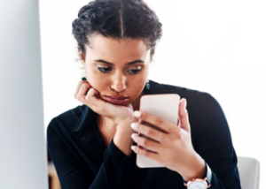 Woman looking at phone disappointedly.