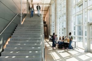 The staircase of a campus building, with students gathered around laptops in the mezzanine.