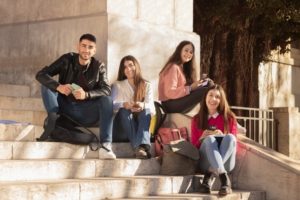 Posed photo of students facing the camera, sitting on campus building steps