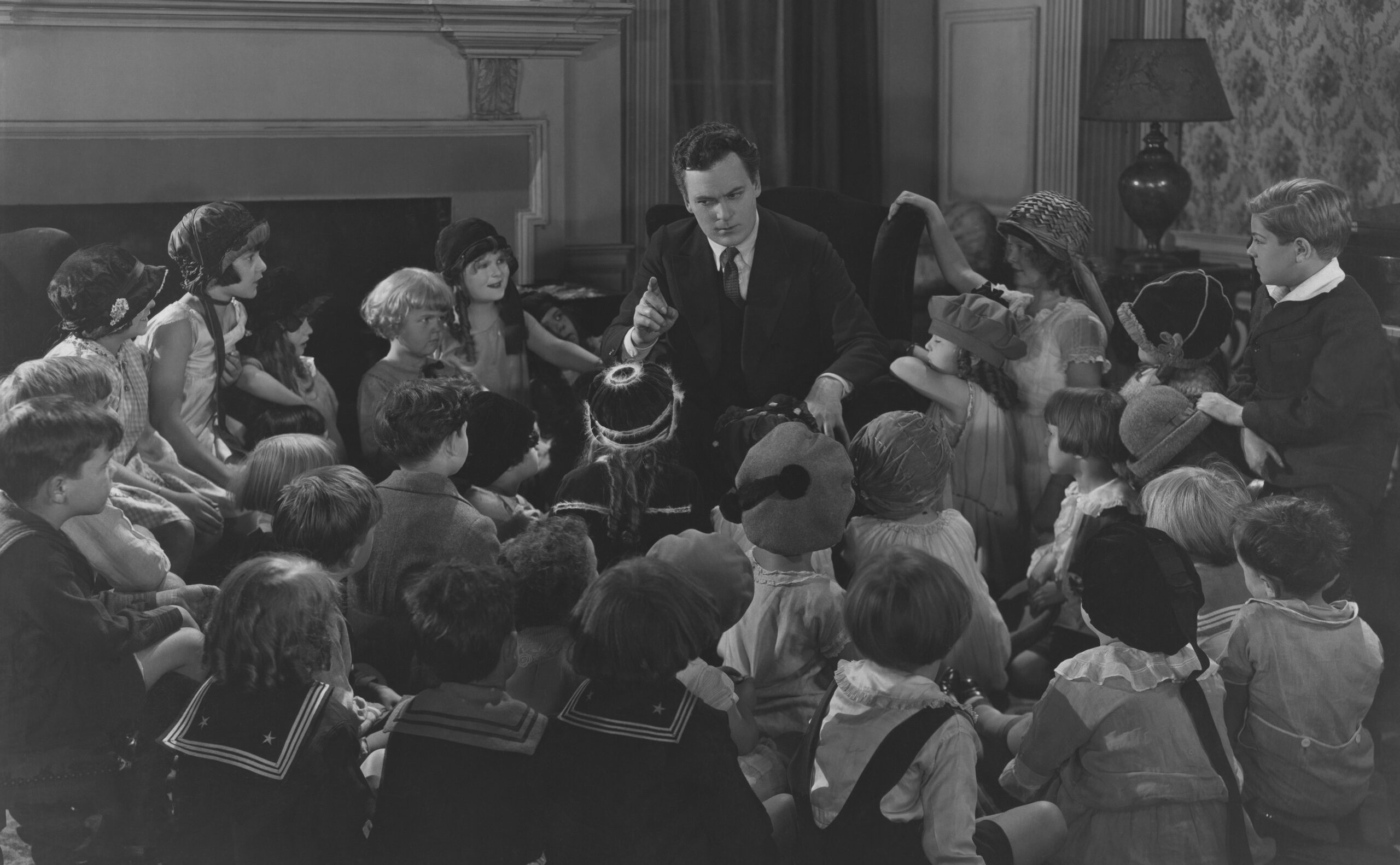 vintage photo of adult telling a story to a group of children sitting on the floor in a semi-circle around him