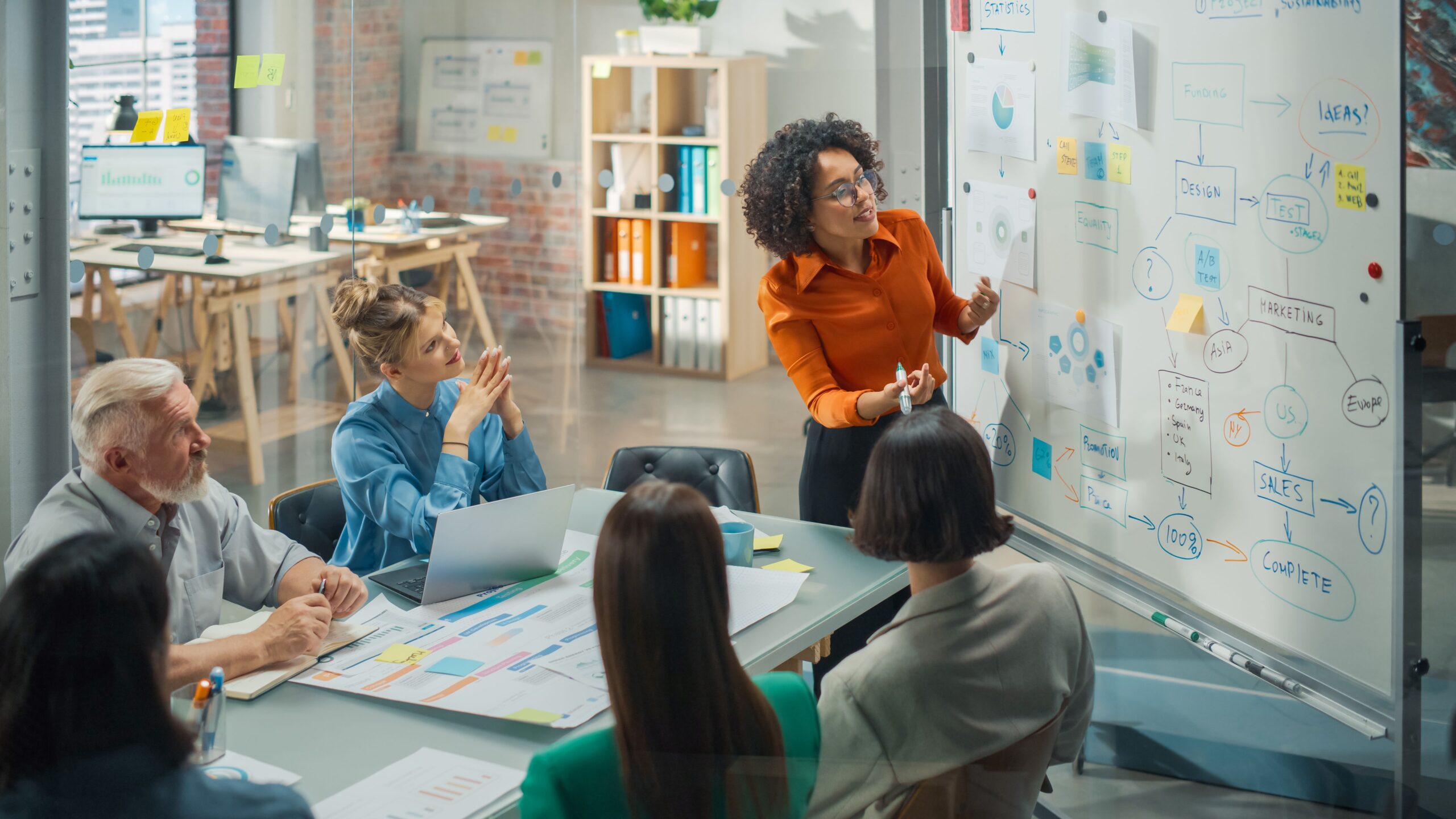 Group of young coworkers looking at a white board in an office