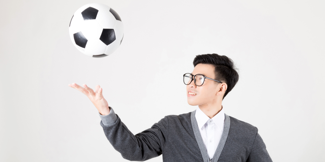 Asian male college student throwing a soccer ball in the air