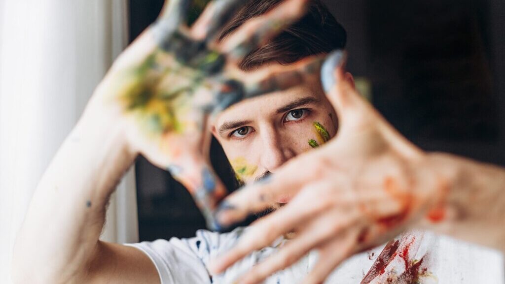 Man framing his face with his paint-covered hands