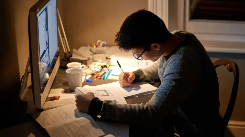Male sitting at desk working on paperwork.