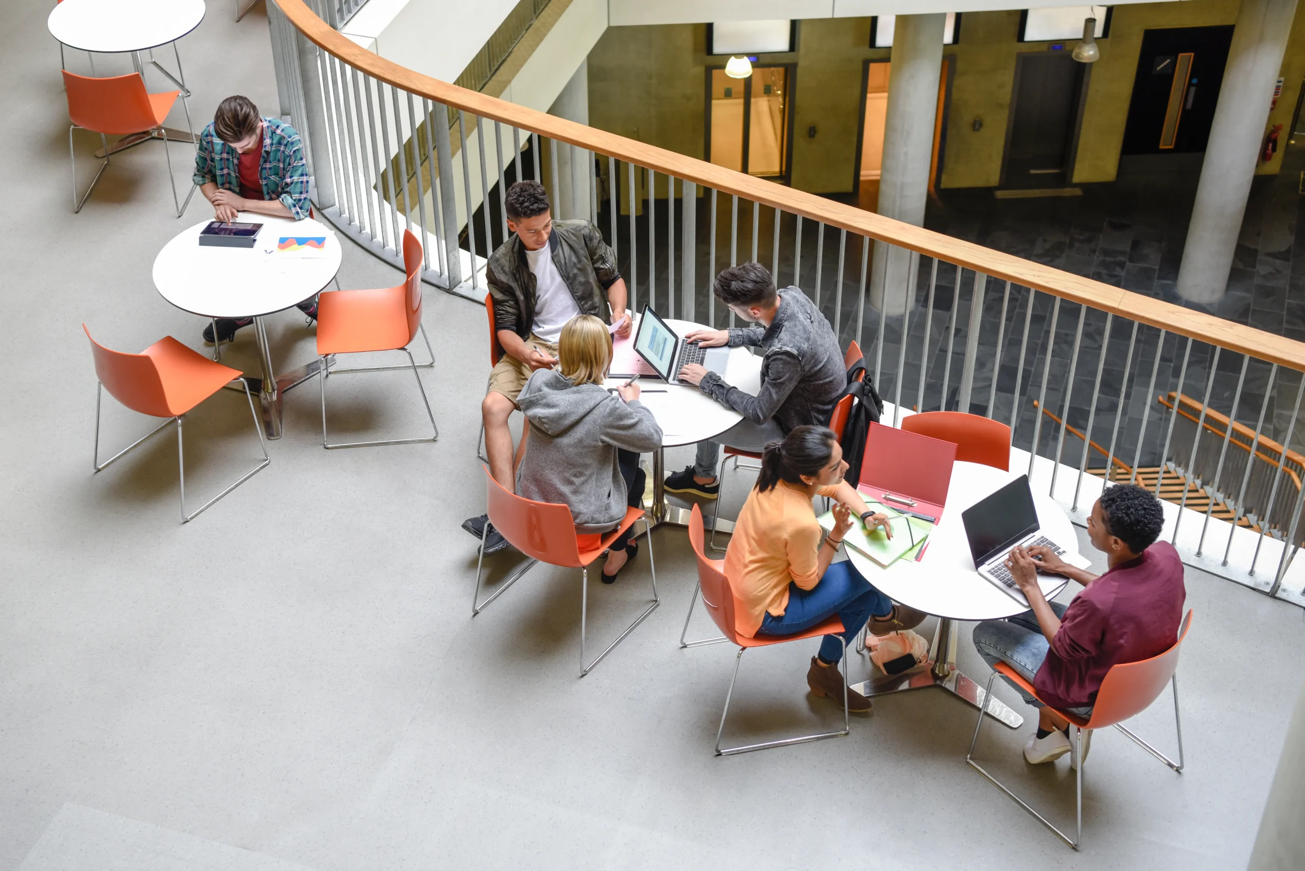 Students sitting at tables in atrium.
