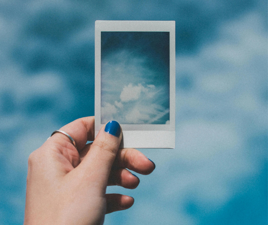 Person holding a photo of clouds against a cloud background