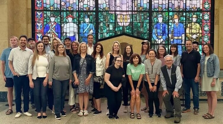 group of coworkers in front of a stained glass window